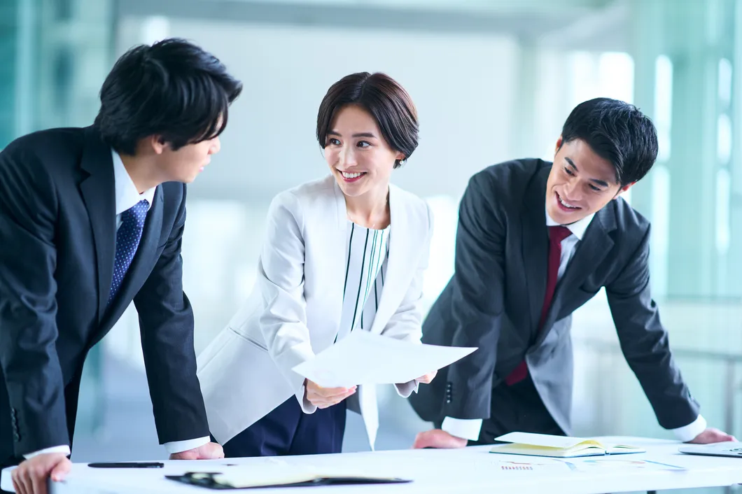 デスクで書類を見ながら話し合うビジネスパーソンたち