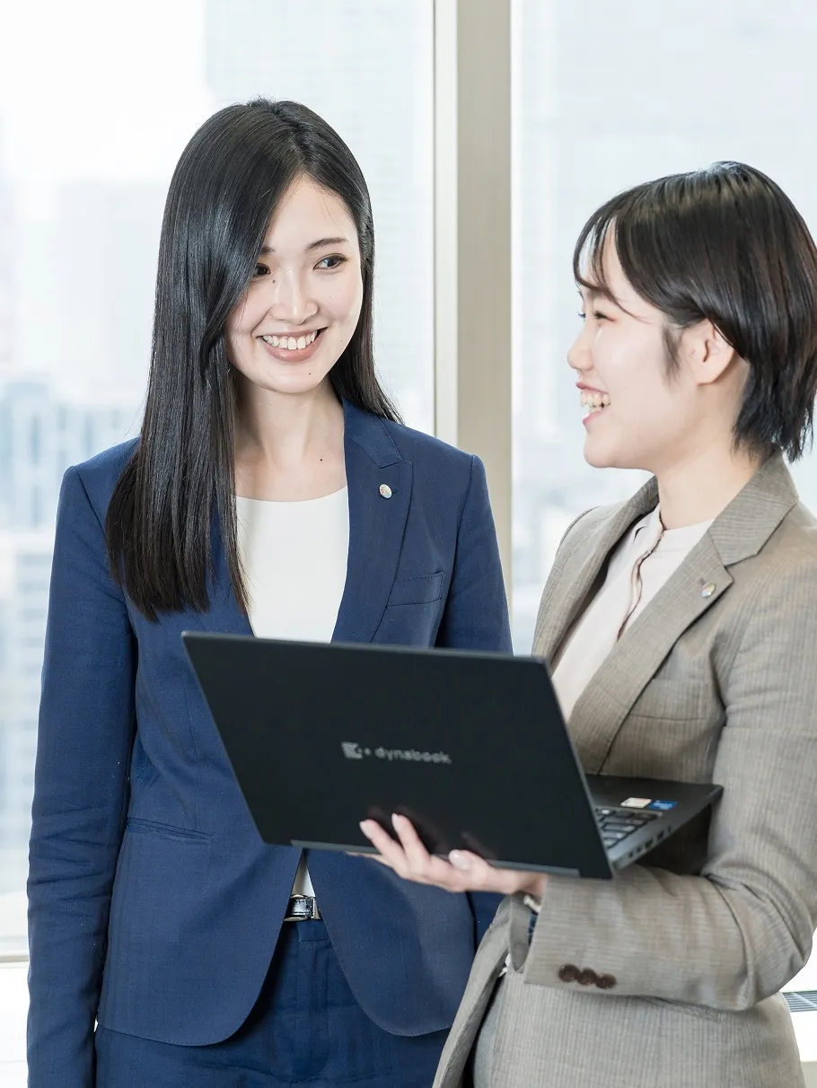 スーツを着た女性2人が笑顔で話をしている様子