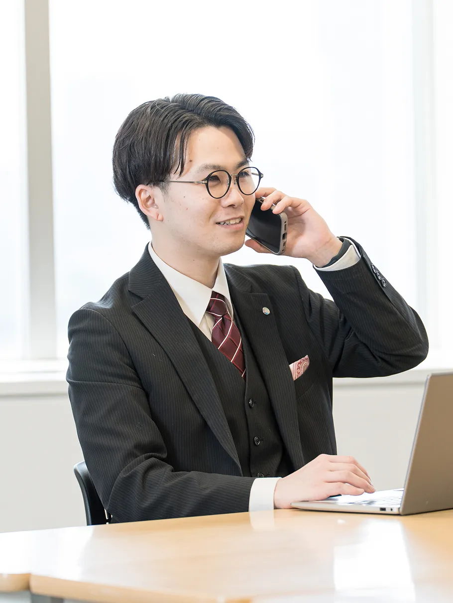 スーツを着た男性が笑顔で電話をしている様子