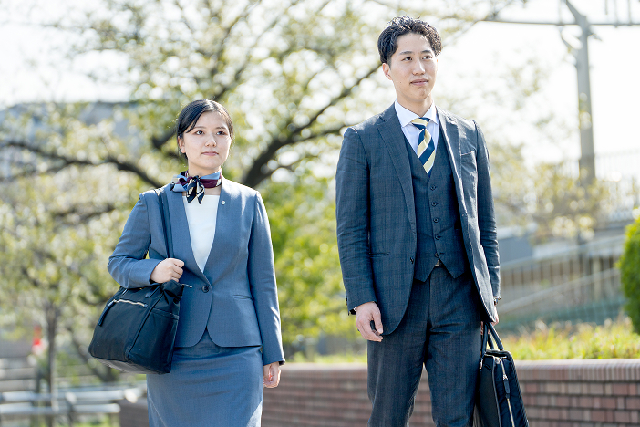 スーツを着た女性と男性が外を歩く様子