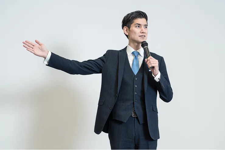 スーツ姿の男性がマイクを持って話をしている様子